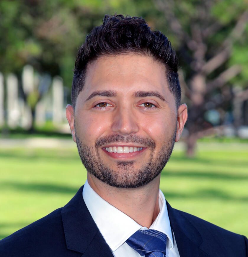 Portrait of Joel Novelliere in a navy suit, outdoors.
